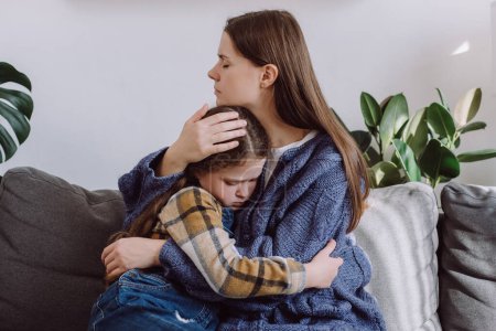 Photo for Caring young mommy embrace little frustrated child sit on sofa together at home. Loving caucasian mother supports disappointed unhappy daughter kid sympathizing. Making peace after scolding concept - Royalty Free Image