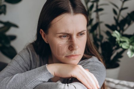Photo for Close up portrait sad lonely woman sitting on sofa alone at home looks frustrated feel worried suffers from break up, psychological concerns, need professional counsellor help, think about problems - Royalty Free Image