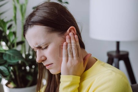Photo for Sick sad young woman has ear pain or earache, hand touch plug ear, suffering painful otitis from loud or noisy sound, inflammation. Health care nerve deaf eardrum disease. Tinnitus concept - Royalty Free Image