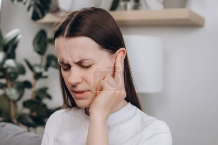 Unhappy upset young caucasian female 25s have ear pain or earache, sad woman suffering painful otitis from loud or noisy sound, inflammation. Health care nerve deaf eardrum disease. Tinnitus concept