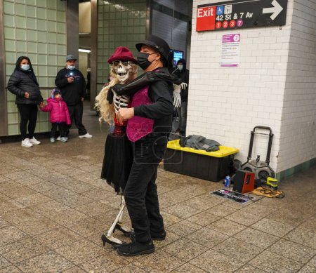 Téléchargez les photos : NEW YORK - 10 MARS 2022 : Man Slow Dances With Skeleton Woman in Times Square 42 St Subway Station in Manhattan. Propriété de la NYC Transit Authority, le métro compte 469 stations en exploitation - en image libre de droit