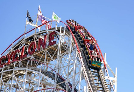 Photo for BROOKLYN, NEW YORK - APRIL 13, 2023: People riding the famous historical landmark Cyclone roller coaster in the Coney Island section of Brooklyn. Cyclone is a historic wooden roller coaster opened on June 26, 1927 - Royalty Free Image
