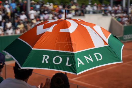 Foto de PARÍS, FRANCIA - 2 DE JUNIO DE 2023: Aficionados al tenis no identificados bajo el paraguas durante el día soleado en 2023 Roland Garros en París, Francia - Imagen libre de derechos