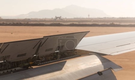 El avión aterriza en el campo de aviación. Spoilers y aletas de borde de arrastre al aterrizar. Vista de la tierra desde el ala del avión. Sinaí. Sharm El Sheikh, Egipto.