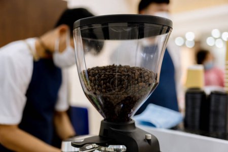 Téléchargez les photos : Grains de café dans le moulin à café électrique. Grains de café fraîchement torréfiés dans la machine de moulin à café. grains de café dans caf. - en image libre de droit