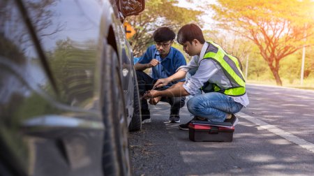 Photo for Emergency roadside assistance, technician helps with wheel replacement. Man changing wheel on a roadside. Roadside assistance - Royalty Free Image