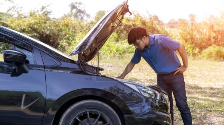 Photo for The car broke down, problem under the hood, the driver serious. man looks at the engine of the car. The driver is the man near the broken car. Man having car troubles - broken down on the side. - Royalty Free Image