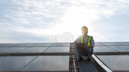 Téléchargez les photos : Configuration de travail de l'ingénieur Panneau solaire sur le toit. Ingénieur ou travailleur travaillent sur des panneaux solaires ou des cellules solaires sur le toit du bâtiment commercial - en image libre de droit