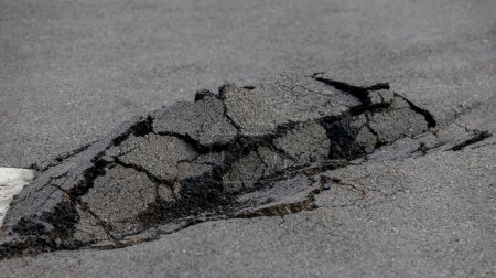 Téléchargez les photos : Route asphaltée endommagée. route fissurée après tremblement de terre. Faible surface d'asphalte. - en image libre de droit