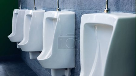 Photo for Toilet men's room. Row of outdoor urinals men public toilet, Closeup white urinals in men's bathroom, design of white ceramic urinals for men in toilet room. Empty advertisement in public toilet - Royalty Free Image
