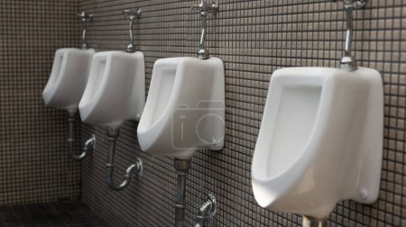Photo for Toilet men's room. Row of outdoor urinals men public toilet, Closeup white urinals in men's bathroom, design of white ceramic urinals for men in toilet room. Empty advertisement in public toilet - Royalty Free Image