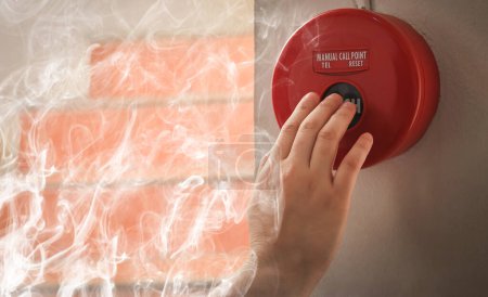 Téléchargez les photos : Contremaître ou travailleur poussant l'alarme incendie sur le mur. Un feu ! ou Cas d'urgence au bâtiment de l'usine. Équipement d'alarme ou d'alerte incendie ou d'alarme cloche - en image libre de droit