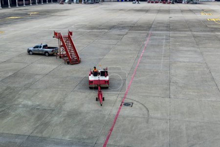 Photo for Airplane tow tractor at the airport apron near the terminal. Aircraft Towing Tractor.  A towing tractor belonging in air port is being operated by officer. Aerodrome tow tractor is driving at airport - Royalty Free Image