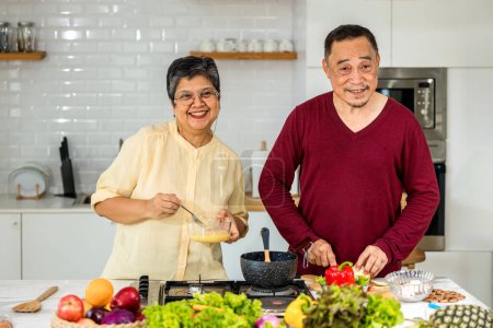 Ein älteres asiatisches Ehepaar lebt glücklich in der heimischen Küche. Älteres Paar kocht in einer Küche. Glückliches, reifes Ehepaar in der Küche, Aktive Senioren. Beziehung und Aktivität älterer Menschen
