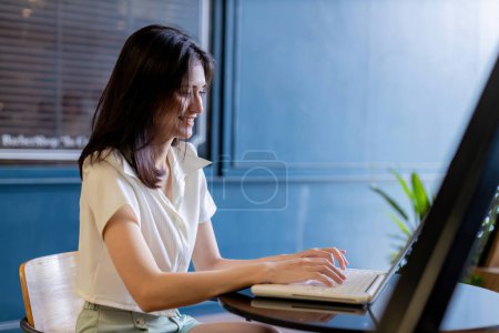 Woman working on laptop computer sitting at home and managing her business via home office during Coronavirus or Covid-19 quarantine. woman using laptop and smiling while working at Home