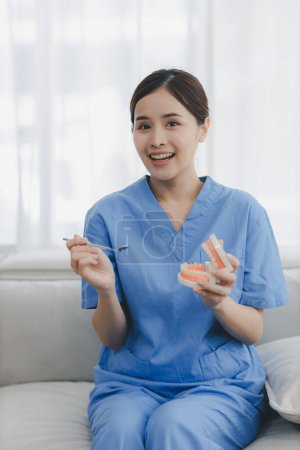 Ein Zahnarzt hält einer älteren Frau den Mundspiegel eines Prothesenmodells vor und zeigt ihr, wie sie sich um ihre Mundgesundheit kümmert. neue Normalität medizinischer Behandlung, Telemedizin und telemedizinischen Fortschritts. Zähne checken