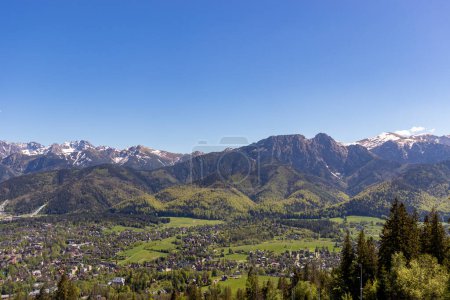 View of Zakopane town from Gubalowka with Tatra mountains range at background in summer, Poland. Popular trekking and nature lovers destination in Poland. Zakopane resort town and high Tatra mountains