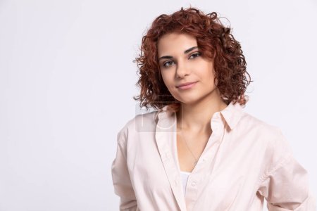 Photo for A gentle smile on her face. A European woman with chestnut-colored hair. A girl with fair skin and curly short hair looks straight ahead. - Royalty Free Image