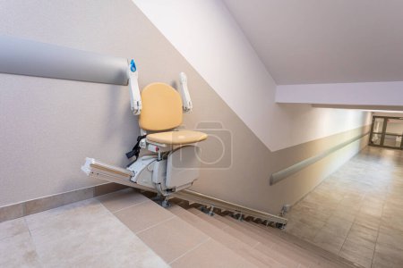 Foto de Ascensor especializado en sillas adosado a escaleras para ayudar a personas con discapacidades de movilidad. Soluciones modernas para las personas. - Imagen libre de derechos
