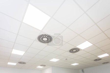 Téléchargez les photos : Les lampes brillent dans le plafond suspendu et le tout vu d'en bas et avec perspective. Plafond moderne et à la mode dans une grande pièce. - en image libre de droit