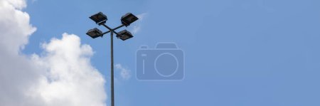 Foto de Marco panorámico sobre alumbrado público moderno. Led lámpara cuádruple en un poste alto contra un cielo con nubes blancas. - Imagen libre de derechos
