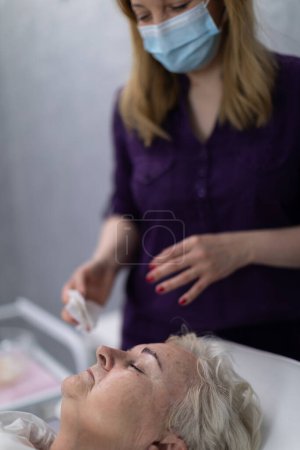 Photo for Blurred background. In the background can be seen the figure of a woman wearing a purple button-down jacket. In the foreground is a close-up on the face of a woman lying on a bed. The woman has her - Royalty Free Image