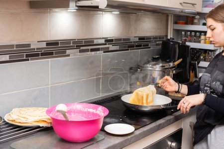 Un joven cocinero lleva un panqueque frito en un plato. Sabrosos panqueques caseros de una mano de mujeres jóvenes.