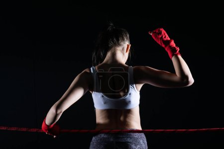 The fighter won her first fight. The woman raised her hands in evidence of winning the fight.