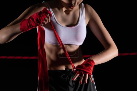 Eine Frau bereitet sich auf einen Kampf vor und wickelt ihre Hände in einen speziellen Boxverband. Starke Frau. Der unvermeidliche Kampf im Ring.