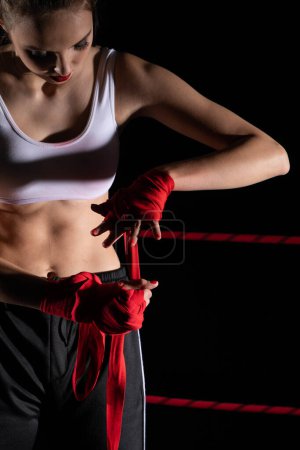 Eine Frau bereitet sich auf einen Kampf vor und wickelt ihre Hände in einen speziellen Boxverband. Starke Frau. Der unvermeidliche Kampf im Ring.