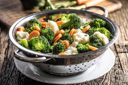 Steamed broccoli, carrots and cauliflower in a stainless steel steamer. Healthy vegetable concept.