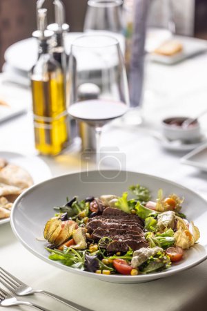 Téléchargez les photos : Table avec steak et salade avec condiments à côté dans un restaurant. - en image libre de droit