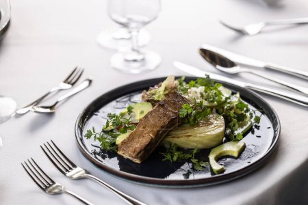 Foto de Lujosa mesa con un plato oscuro lleno de ensalada vegetariana con tofu marinado. - Imagen libre de derechos