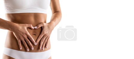 Middle part of female body with heart shape from hands. A woman in underwear symbolizes a healthy lifestyle, a healthy stomach, menstruation or pregnancy. Isolated on white.