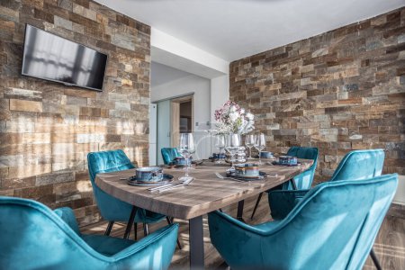 Téléchargez les photos : Salle à manger avec table en bois et chaises bleues au sol dans un appartement moderne. - en image libre de droit