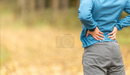 Photo for Young man with an athletic figure and a lower back injury. Back pain during sports. - Royalty Free Image