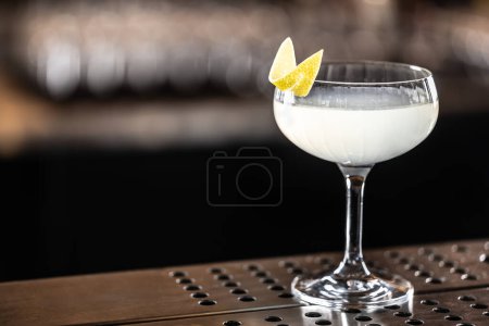 Foto de Refrescante cóctel francés 75 decorado con cáscara de limón en un vaso en el bar. - Imagen libre de derechos