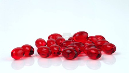 Foto de Cápsulas ovaladas transparentes rojas con vitaminas. Aislado sobre un fondo blanco. - Imagen libre de derechos