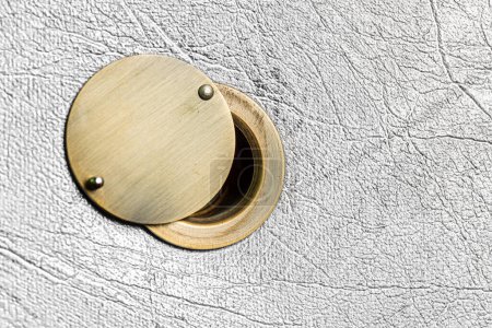 Téléchargez les photos : Peephole avec amortisseur ouvert sur une porte légère texturée. - en image libre de droit