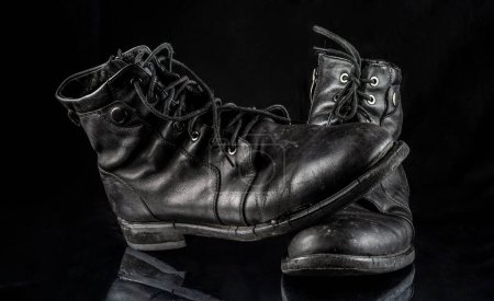 Photo for A pair of worn men's leather boots on a black background. - Royalty Free Image