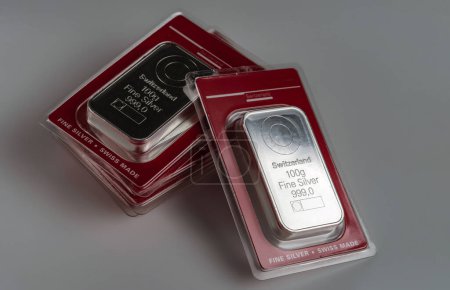 Foto de Several minted silver bars weighing 100 grams in transparent blister pack on a grey background. - Imagen libre de derechos
