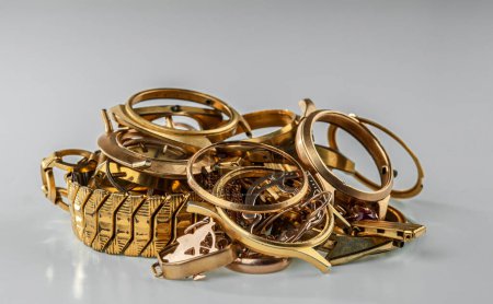 Téléchargez les photos : A scrap of gold. Old and broken jewelry, watches of gold and gold-plated on a grey background. - en image libre de droit