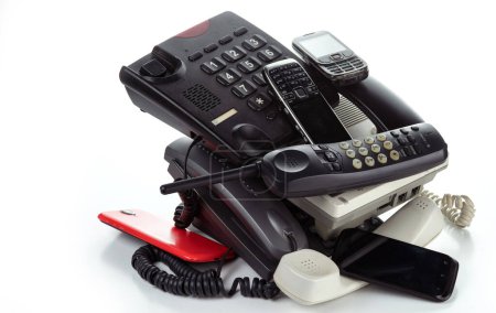Foto de Montón de viejos teléfonos de escritorio, teléfono inalámbrico y teléfonos inteligentes sobre un fondo blanco - Imagen libre de derechos