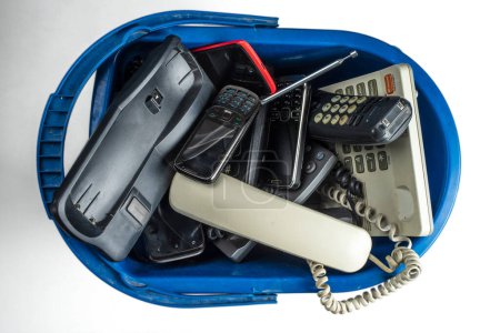 Foto de Teléfonos de escritorio antiguos, teléfonos inalámbricos, teléfonos celulares y teléfonos inteligentes en un bote de basura aislado sobre un fondo blanco. - Imagen libre de derechos