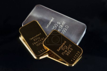 Gold- und Silberbarren unterschiedlichen Gewichts isoliert auf schwarzem Hintergrund.