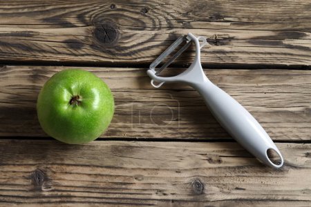 Téléchargez les photos : Couteau pour le nettoyage des fruits et légumes avec pomme verte sur un fond de texture rugueuse en bois - en image libre de droit