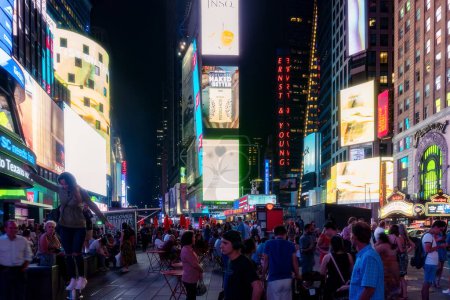 Foto de Nueva York, Estados Unidos - 9 de agosto de 2019: Personas y turistas pasean entre las luces y los rascacielos de Time Square en Manhattan durante una noche de verano - Imagen libre de derechos