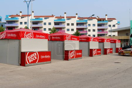 Téléchargez les photos : Torres Vedras, Portugal - juin 27, 2023 : Cinq tentes Red Super Bock se dressent dans une rangée dans la rue, sur fond de maison avec des balcons colorés. - en image libre de droit