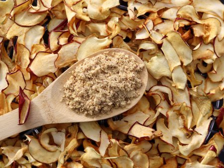 Téléchargez les photos : Farine de pomme dans une cuillère en bois sur un fond de pommes séchées. Poudre de pectine de pomme - en image libre de droit