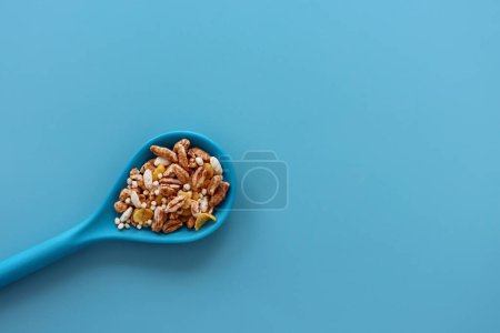Eine Mischung aus Luftflocken in einem blauen Löffel auf blauem Hintergrund. Haferflocken, Quinoa, Reis und Cornflakes